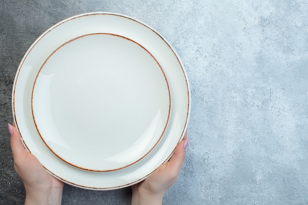 Hand met witte platen aan de rechterkant op halfdonker lichtgrijs oppervlak met verweerd grofkorrelig verloopoppervlak