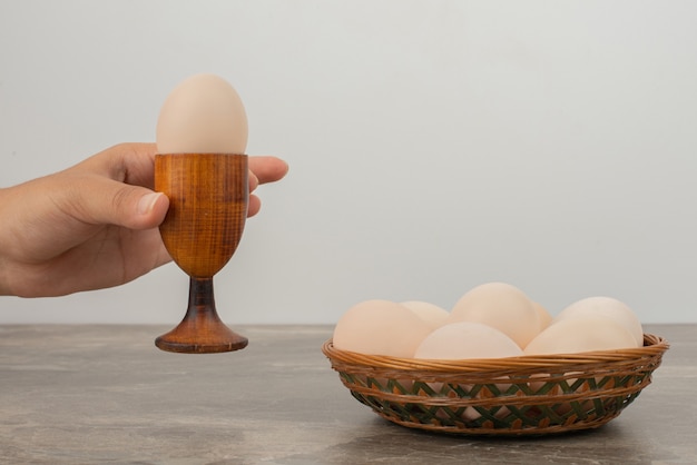 Hand nemen van een kopje ei en een mandje met witte eieren.
