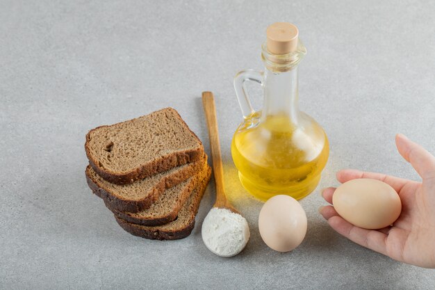 Hand openen van een glazen fles olie met sneetjes brood.