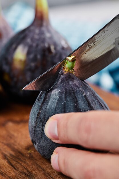 Hand snijden een vijg op houten snijplank.