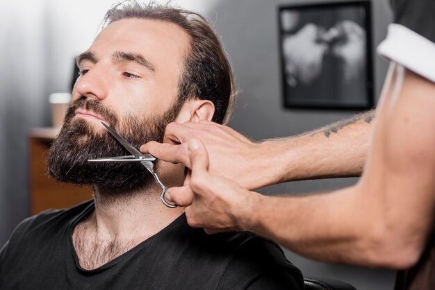 Hand van de baard het stileren man baard met een schaar