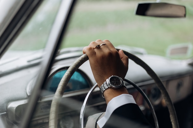 Hand van een man op het stuur van een ouderwetse auto, man's horloge