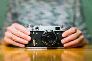 Gratis foto handen aanraken van de camera op tafel