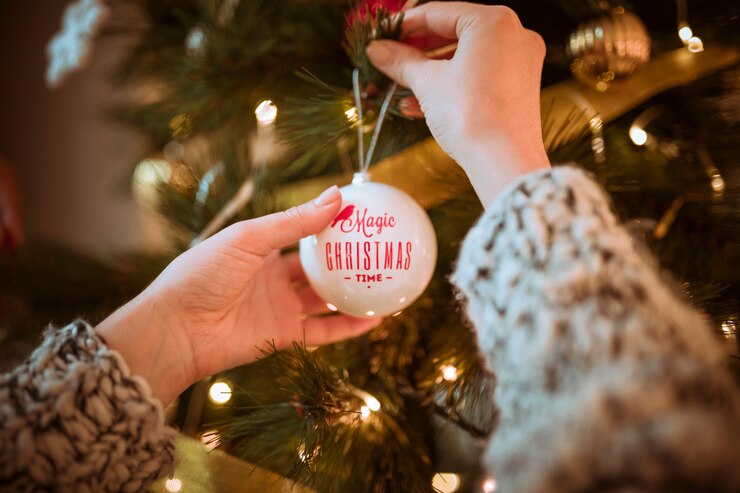 Gratis Foto handen die bal op kerstboom zetten