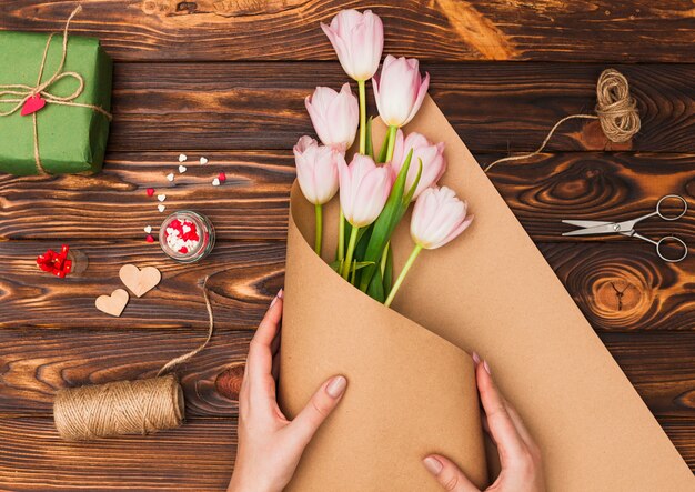 Handen die bloemen op houten lijst verpakken