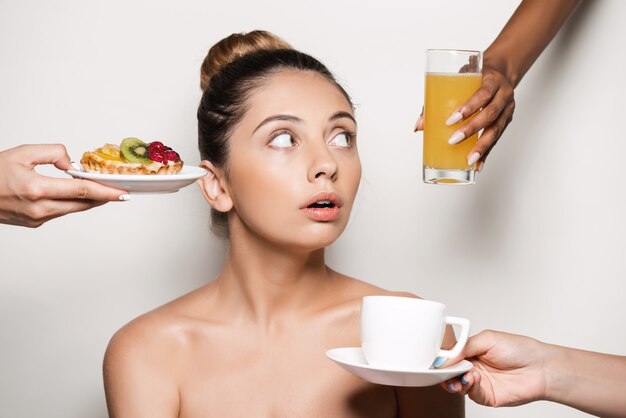 Handen die cake en dranken aanbieden aan jonge mooie vrouw