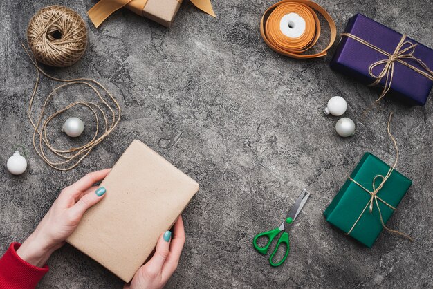 Handen die de giftdoos van Kerstmis met koord en schaar houden