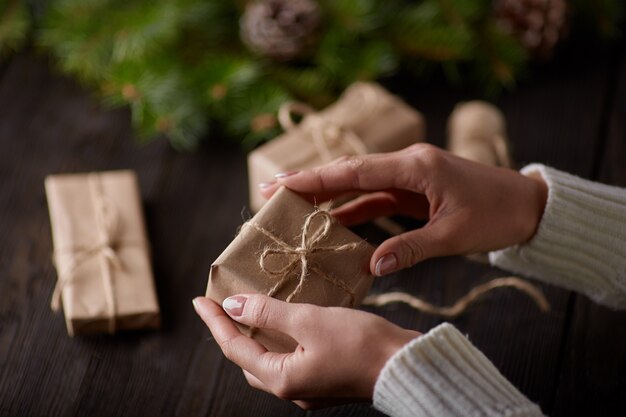 Handen die dozen met bruine geschenken met string