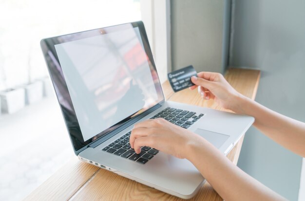 Handen die een creditcard en het gebruik van laptop computer voor online