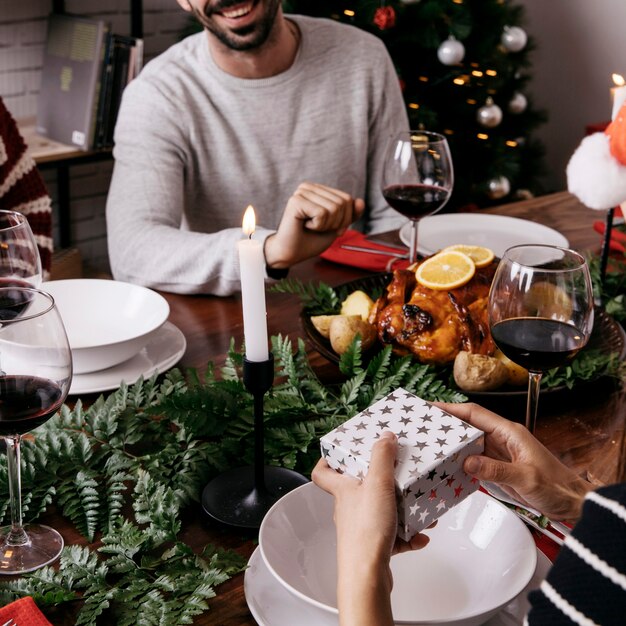 Handen die een geschenkdoos vasthouden bij het kerstdiner