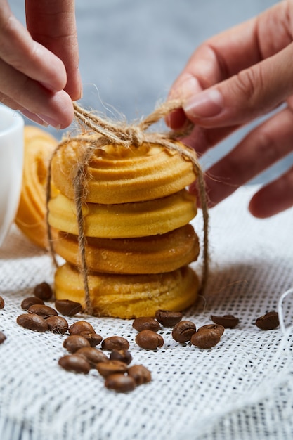 Handen die een stapel koekjes met koffiebonen binden.