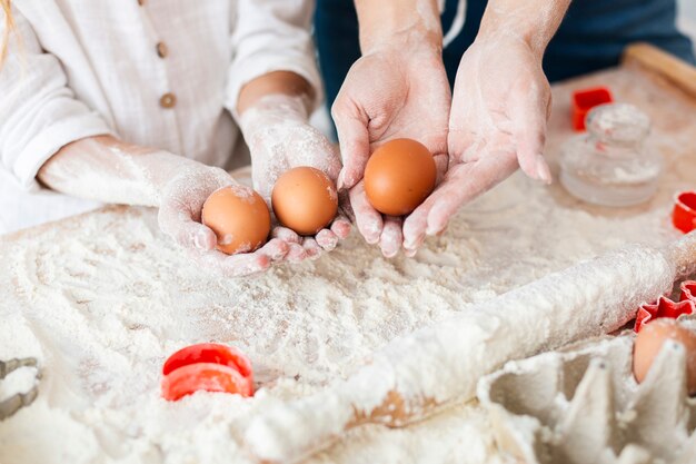 Handen die eieren houden om deeg te maken