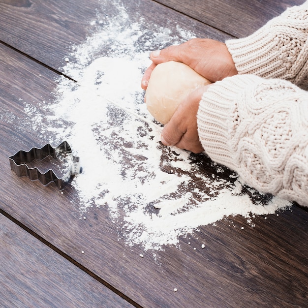 Handen die gebakje met koekjesvorm naast maken