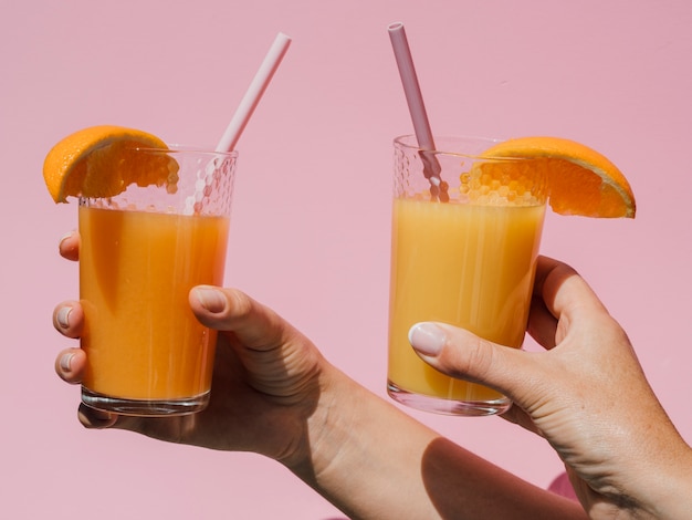 Handen die glazen met natuurlijk jus d'orange vooraanzicht houden