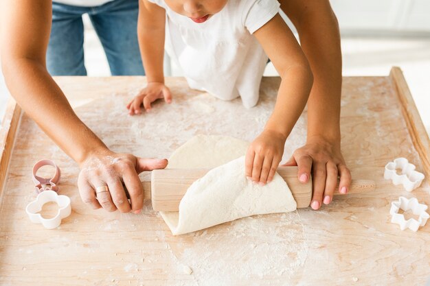 Handen die keukenrol op koekjesdeeg gebruiken