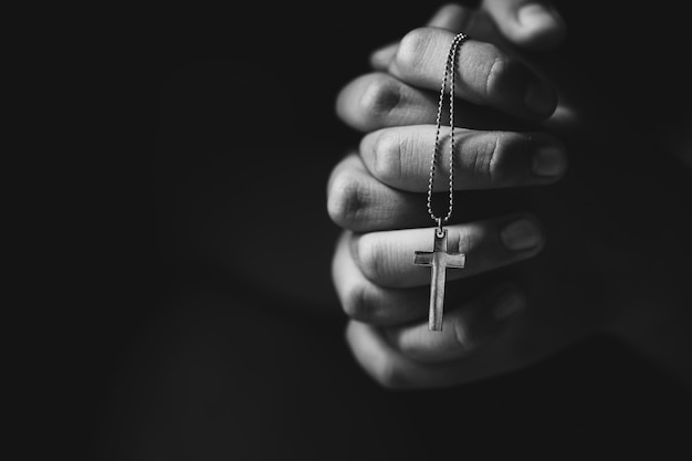 Handen die kruis houden tijdens het bidden.