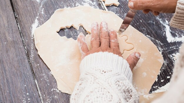 Handen die man gevormd koekje snijden van gebakje