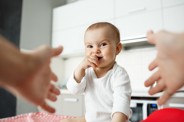 Handen die reiken om schattige glimlachende baby te houden