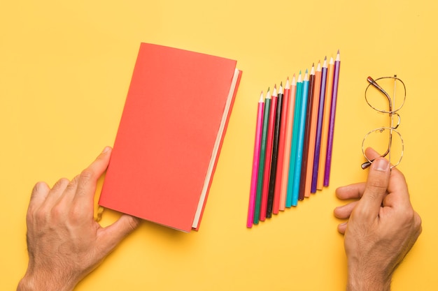 Gratis foto handen die sketchbook dichtbij met potloden houden