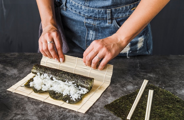 Gratis foto handen doen wrap met sushi mat