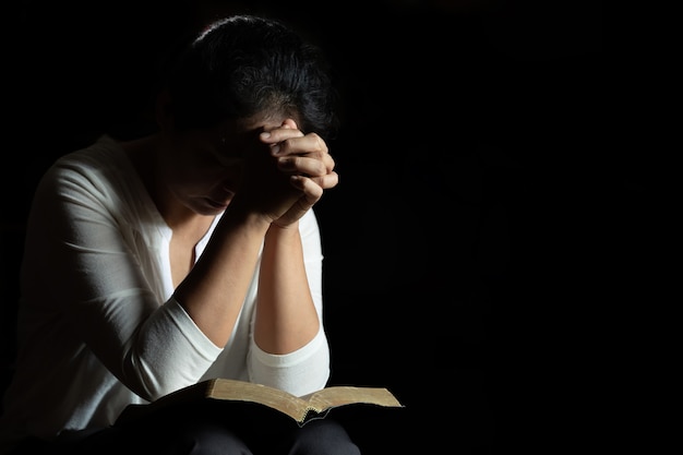 Handen gevouwen in gebed op een Heilige Bijbel in de kerk