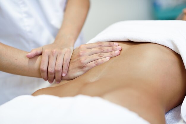 Handen masseren vrouwelijke buik.Therapeut het toepassen van druk op de buik.