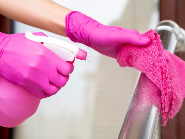 Handen met chirurgische handschoenen die leuning met doek en wassing schoonmaken