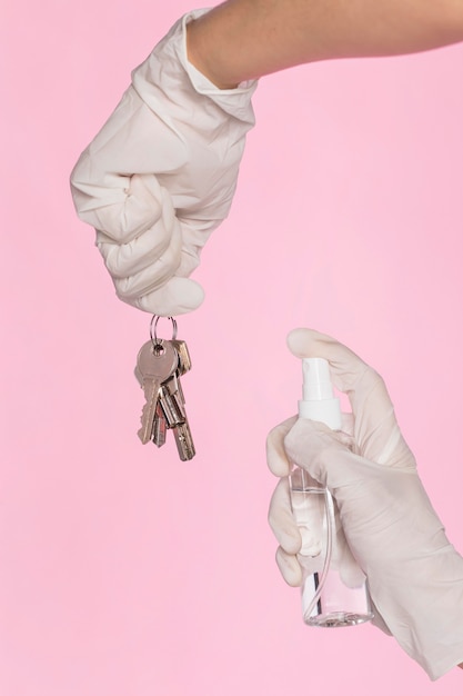 Handen met chirurgische handschoenen die sleutels desinfecteren