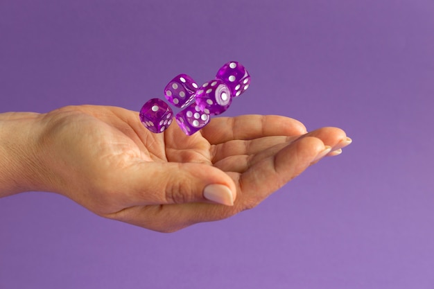 Handen met dobbelstenen op paarse achtergrond