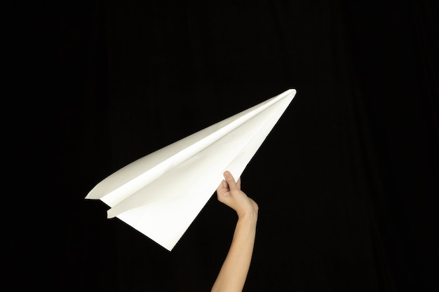 Handen met het teken van papieren vliegtuigje of bericht op zwarte achtergrond