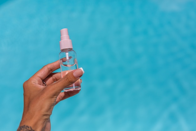 handen met kleine fles looien olie vloeistof over blauwe zwembad