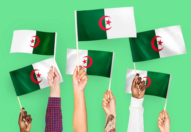 Handen met vlaggen van Algerije zwaaien