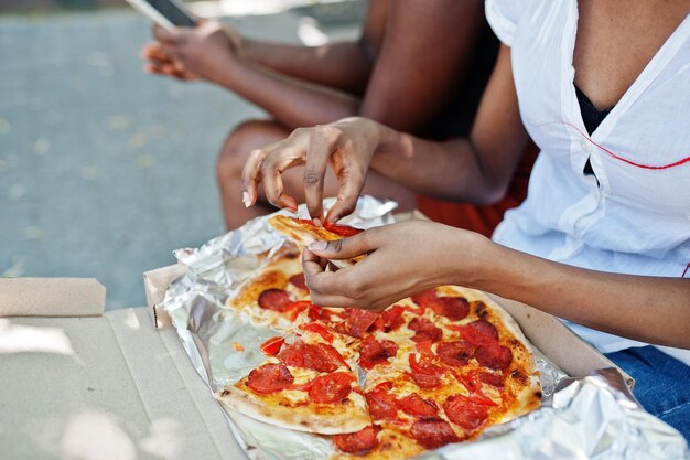 Handen van Afro-Amerikaanse vrouw met pizza