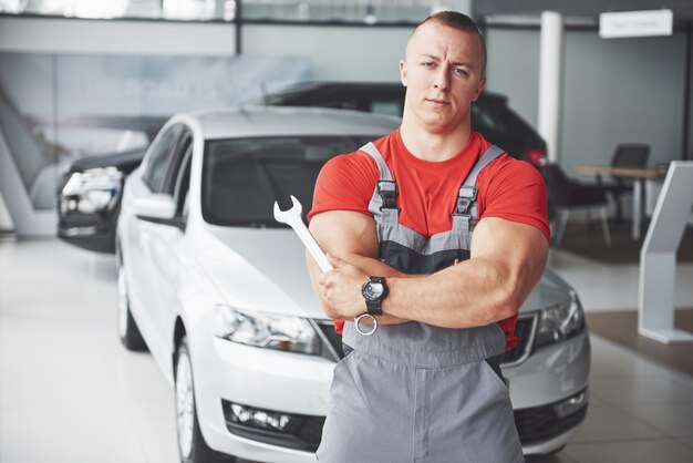 Handen van automonteur met moersleutel in garage.