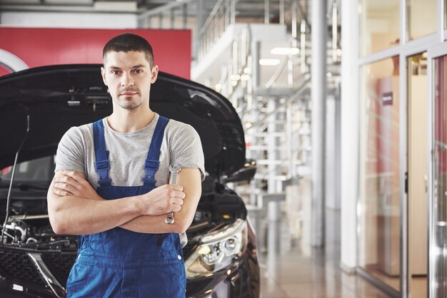 Handen van automonteur met moersleutel in garage.