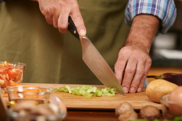 Handen van de onherkenbare mens die verse groenten snijden