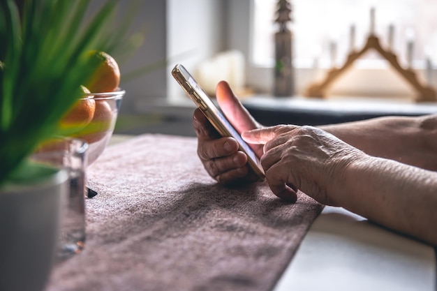 Gratis foto handen van een bejaarde die een mobiele telefoon houdt