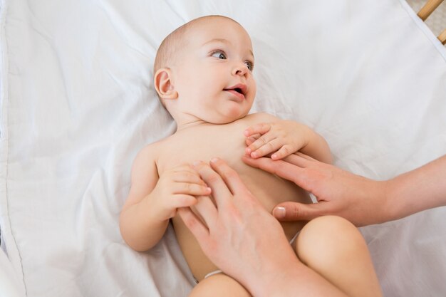 Handen van een moeder speelt met baby jongen op een wieg