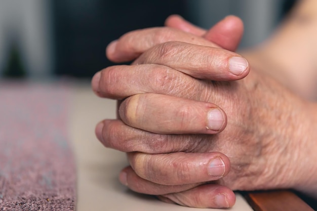 Handen van een oude vrouw gevouwen voor gebed