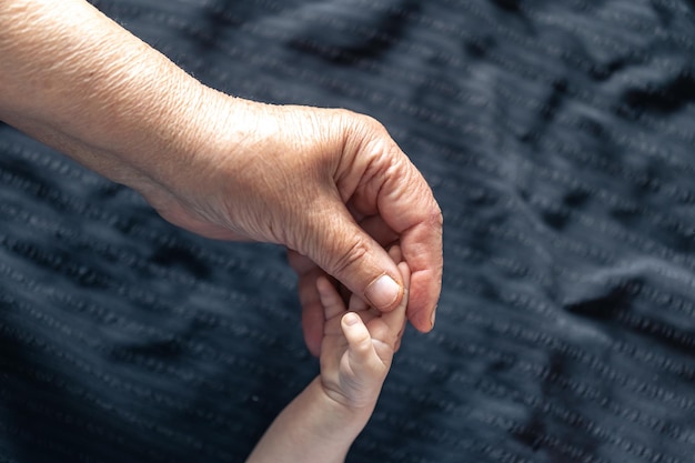 Handen van een oudere persoon en een kleine baby van dichtbij