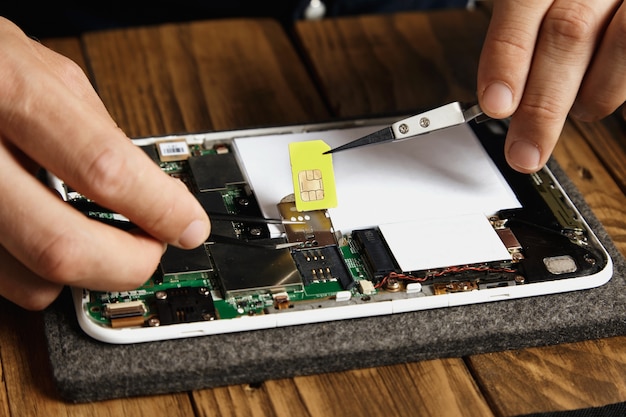 Handen verwijderen gsm simkaart uit nest op moederbord in elektronisch apparaat dat kapot was