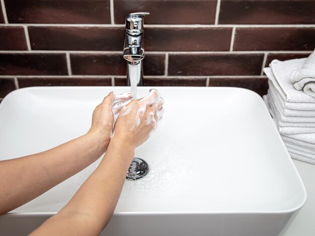 Handen wassen met zeepachtig water onder stromend water. Het concept van persoonlijke hygiëne en gezondheid.