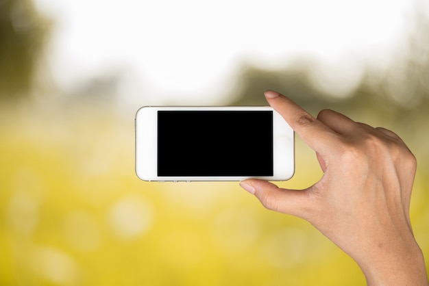 Handgreep en slimme telefoon, tablet, cellphone op daglicht met gele vage aardachtergrond.