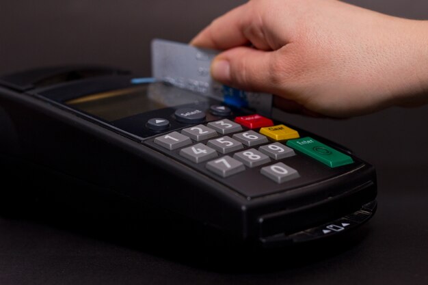 Handwisselen van creditcard in de winkel. Vrouwelijke handen met creditcard en bank terminal. Kleurafbeelding van een POS en creditcards.