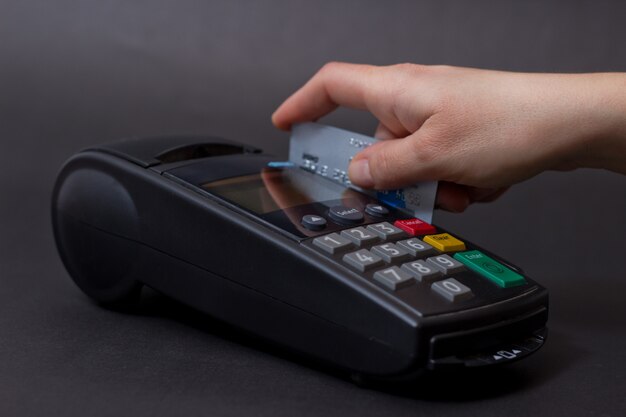 Handwisselen van creditcard in de winkel. Vrouwelijke handen met creditcard en bank terminal. Kleurafbeelding van een POS en creditcards.