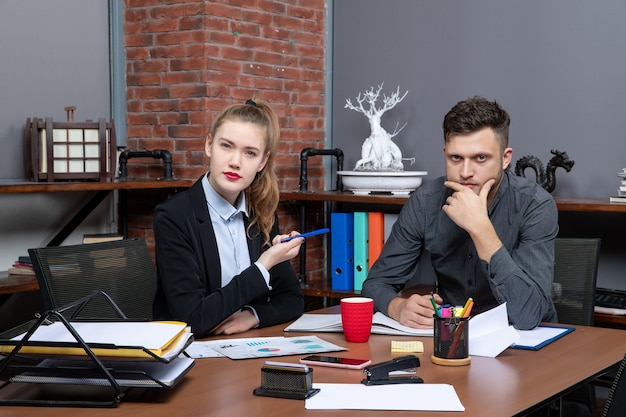 Hardwerkende en drukke professionele werknemers die één probleem bespreken in de documenten op kantoor