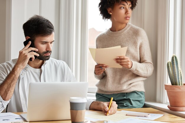 Hardwerkende freelancer gebruikt moderne technologieën, lost problemen op afstand op, schrijft wat informatie in kranten