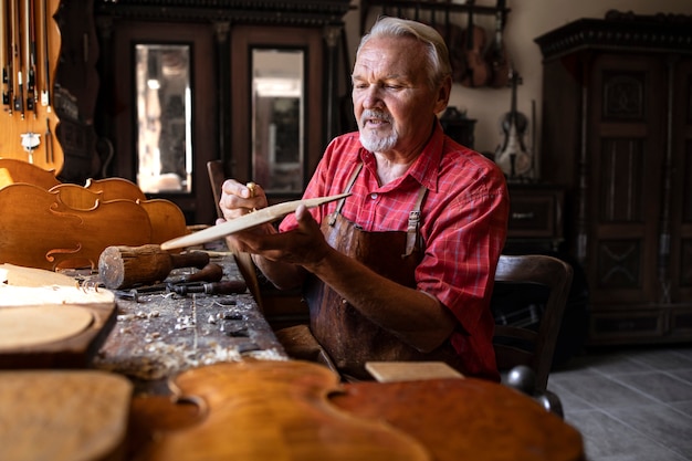 Gratis foto hardwerkende senior timmerman bezig met zijn creatieve project in timmerwerkplaats