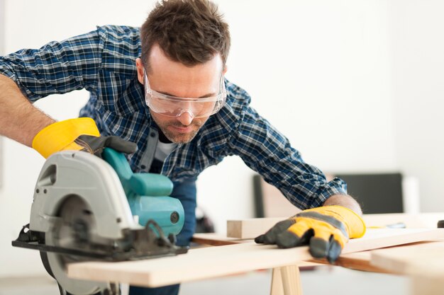 Hardwerkende timmerman die houten plank snijdt