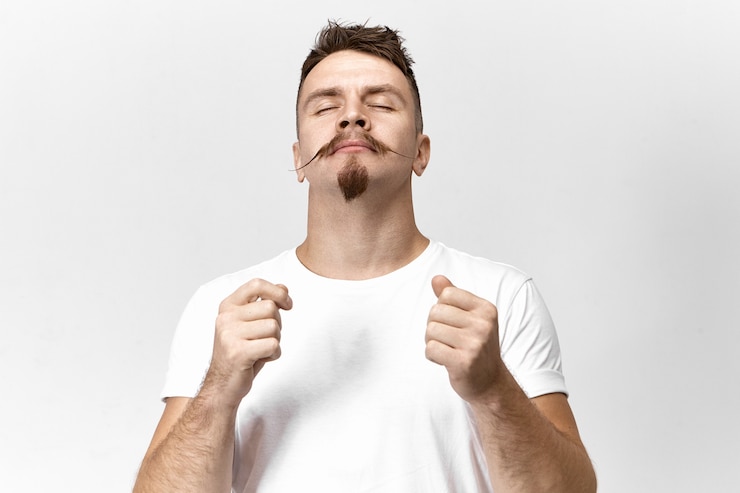 Gratis Foto harmonie, vrede en evenwicht concept. studio shot van knappe stijlvolle jonge man gekleed in wit t-shirt sluitende ogen, kalm tevreden gelaatsuitdrukking, mediteren of luisteren naar mooie muziek